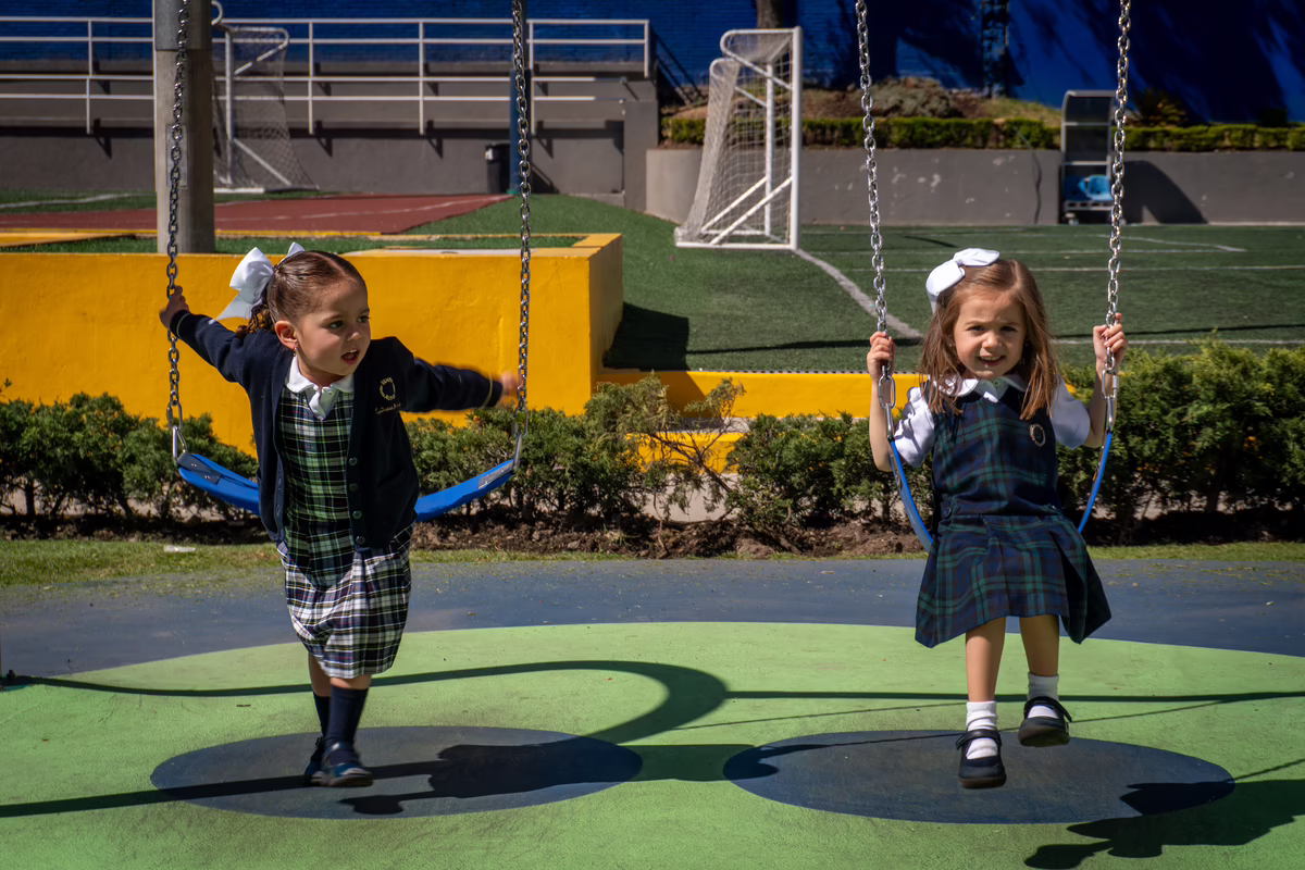 Madre e hija sonriendo en el aula junto a un mapa de México.